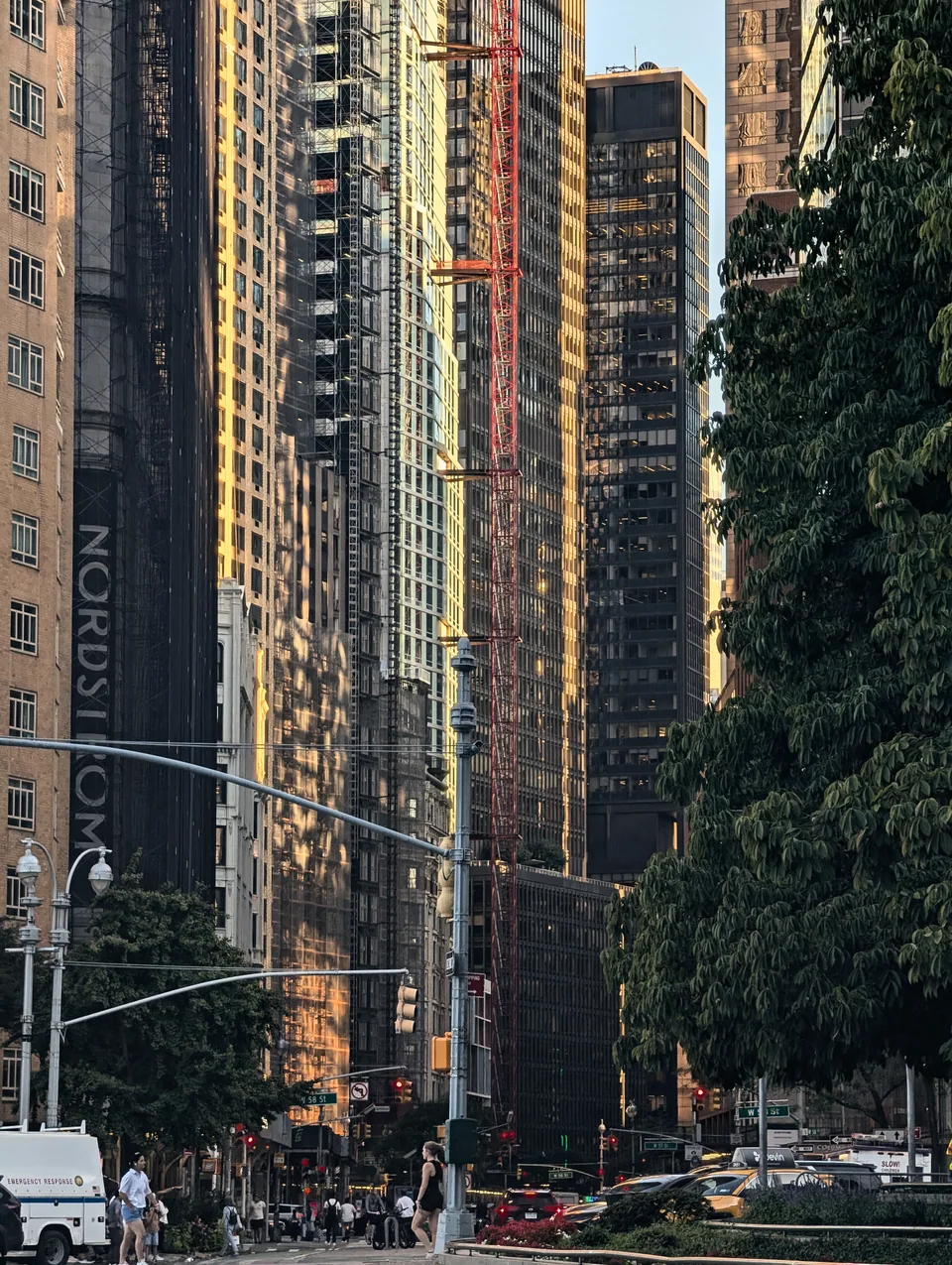Golden evening light on glass towers and a red construction lift.