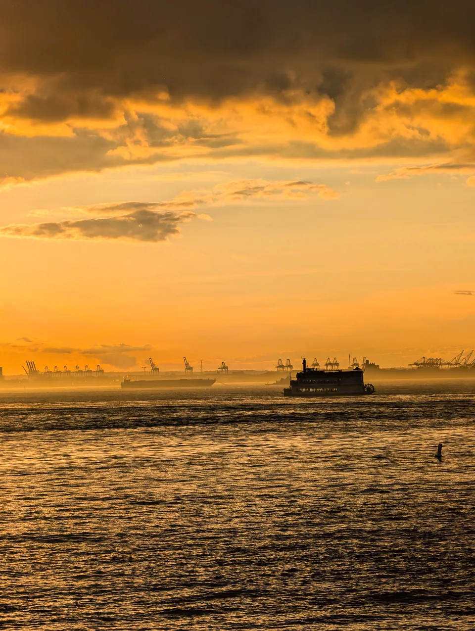 A ferry crossing the river beneath golden clouds.