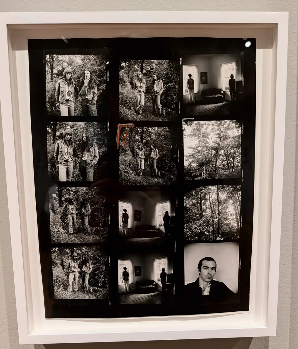 A framed contact sheet of black-and-white photographs on a gallery wall.